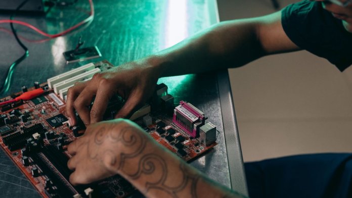 Montaż płyty głównej dla overclockerów Entuzjasta PC składa płytę główną na metalowym biurku w warsztacie